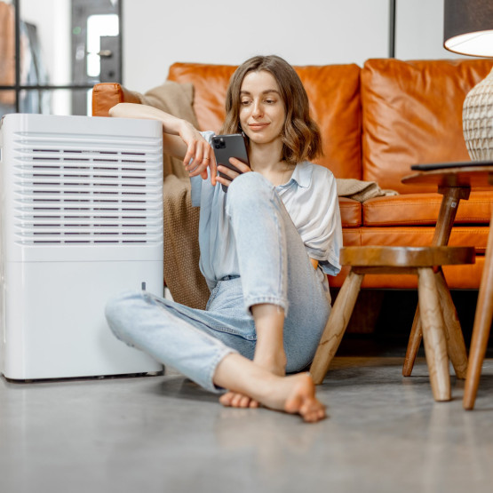 Woman sitting near air purifier and moisturizer appliance